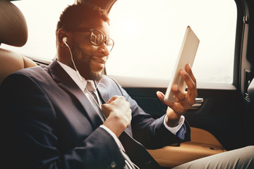 Man in car talks on skype using his tablet. - obrazy, fototapety, plakaty