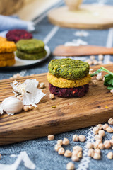 Vegan chickpea burgers cutlets or patties. Healthy vegan diet food. Mixed vegetables yellow pumpkin, orange carrot, green spinach and red beet chickpea cutlets.