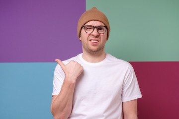 Man wearing glasses points finger aside at questionable distrustful announcement