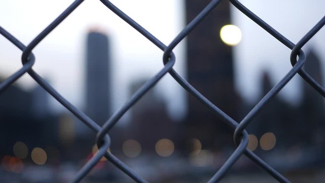 Cinematic bokeh seen near evening city area through chain link fence - V1