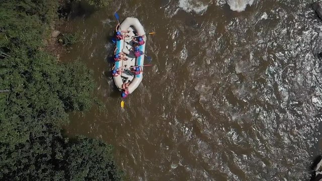 Aerial view group of friends rafting on mountain river. Slow motion group of people enjoying nature kayaking on a mountain river. View from drone.