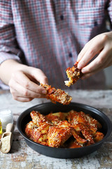 Selective focus. A man eats buffalo wings. Buffalo chicken wings in tomato chili sauce.