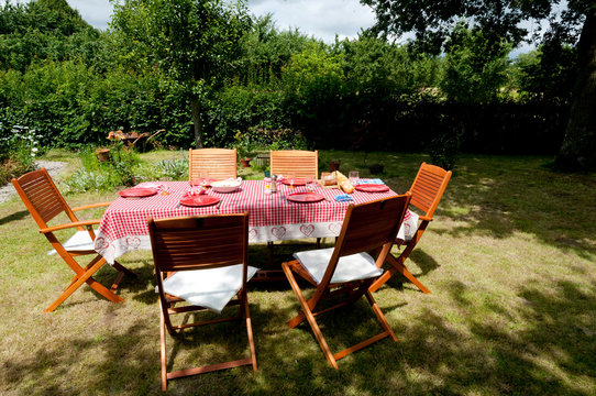 France. Table avec ses couvets dans un jardin. Table with its covers in a garden.