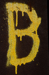 Buchstabe B mit gelber Farbe auf rostigen Untergrund gesprüht