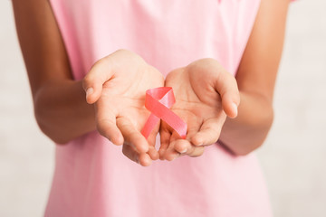 Unrecognizable Woman Holding Pink Ribbon Symbol Standing Over White Background