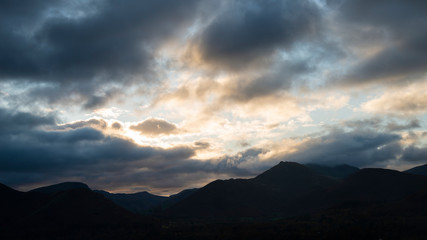 Majestic Autumn Fall landscape image of view from Castlehead in Lake District over Derwentwater towards Catbells and Grisedale Pike at sunset with epic lighting in sky