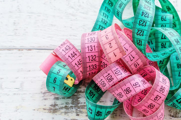 a centimeter-long ribbon of pink and green lies on a wooden table. the concept of a healthy lifestyle. the fight against excess weight