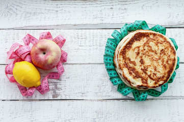 a stack of pancakes on a plate opposite the fruit with a centimeter-long ribbon on the wooden...
