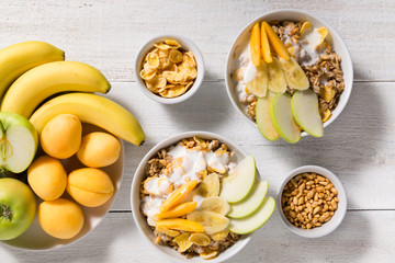 Two plates with oatmeal and a plate of fruit on a white wooden background. Breakfast
