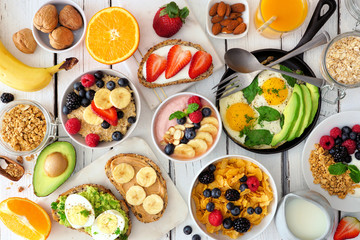 Healthy breakfast table scene with fruit, yogurts, oatmeal, smoothie bowl, cereal, nutritious...