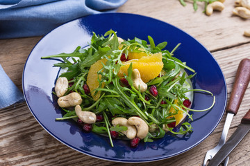 Vegan plant based salad with fresh  arugula, orange, pomegranate seeds, cashews