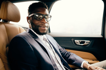 Man in glasses sits in the car in his headphones.