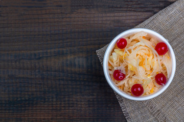 Sauerkraut or fermented cabbage with cranberries in a bowl on rustic wooden background. The concept of proper nutrition and healthy eating. Organic and vegetarian food. Close up, copy space for text