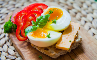 Soft boiled egg on the toasted multi seeded bread with fresh sweet bell pepper and  cheddar cheese, decorated with fresh parsley.