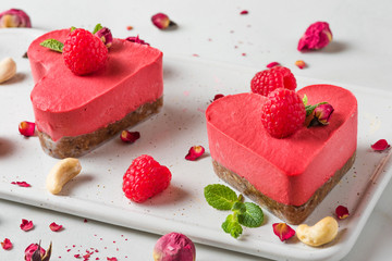 heart shaped red raw vegan cakes with fresh raspberries, mint and dried flowers. Valentines day...