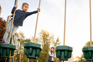 Woman supervising young child on playground at recess