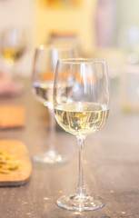 Refreshing white wine in glasses standing side by side on a table with candle in the sun light, blurred background.