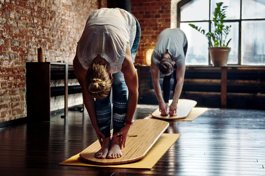 Group of young sporty people, man and woman practicing yoga lesson with instructor, working out, indoor close up image, studio on yoga board