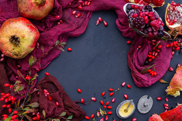 Empty black table with red props and autumn fruits, blank flat lay scene.