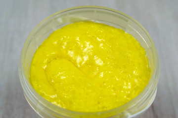 Macro scrub isolated on wooden background. Face body skin peeling sample. Yellow lemon scrub.