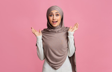 Surprised muslim girl in hijab reising hands in amazement
