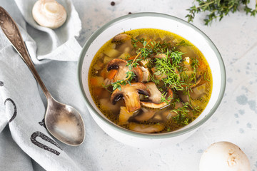 Homemade thick vegetarian mushroom soup with barley and vegetables with herbs in a ceramic bowl on...