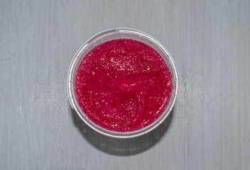 Macro scrub isolated on wood background. Face body skin peeling sample. Pink berry scrub.
