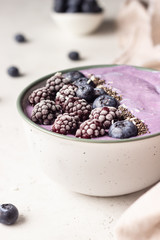Smoothie bowl topped with blueberries, blackberries, chia seeds and coconut flakes. Healthy breakfast berry smoothie bowl.