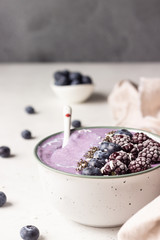 Fototapeta na wymiar Smoothie bowl topped with blueberries, blackberries, chia seeds and coconut flakes. Healthy breakfast berry smoothie bowl.