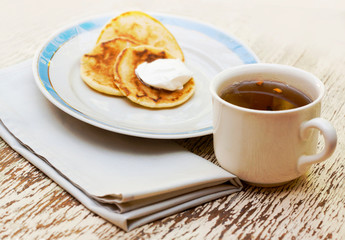 Breakfest set with tea cup and pancakes with cream on the plate