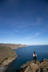 Beautiful woman standing on a cliff with the mediterranean sea in the background