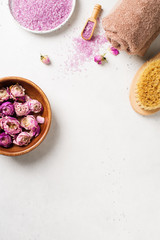 Fototapeta na wymiar Dry rose flowers and pink salt. Wellness and body care flat lay concept