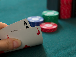 poker chips and ace of spades and ace of hearts on a green cloth casino table gamble