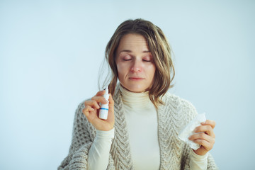 ill modern 40 years old woman with napkin using nasal spray