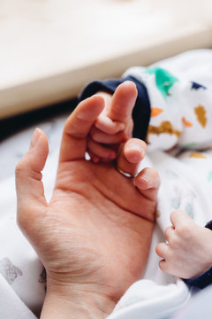 Newborn holding mother's hand. Closeup photography of hands. 