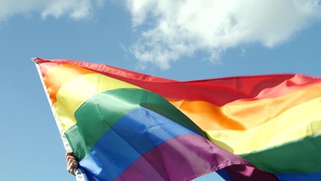 Colorful backlit rainbow gay or lgbt pride flag. Protestor waving LGBT flag at Parade