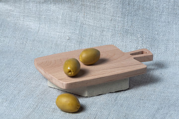 Pitted Canned Green Olives on a small wooden board.