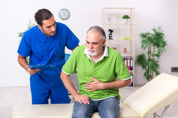 Fototapeta premium Old man visiting young male doctor gastroenterologist