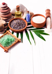 Spa stones with lavender flowers and sea salt on a white wooden background.