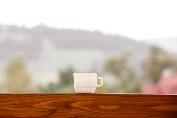 white cup with coffee or tea on the balcony with mountain background