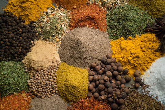 various colored spices and seasonings top view dark background