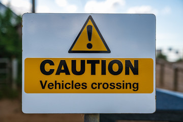 Sign: Caution Vehicles Crossing, with blurry background