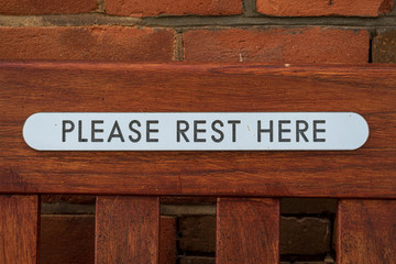 Sign: Please Rest Here - seen on a bench