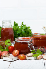 tomato sauces, pasta and fresh ingredients on white wooden background, vertical closeup