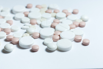 Heap of pills, pharmaceutical medicine tablets and capsules on white background. Drug prescription for treatment medication health care concept, top view with copy space.