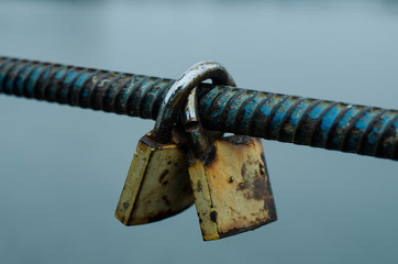 An old rusty padlock hangs on a fence.