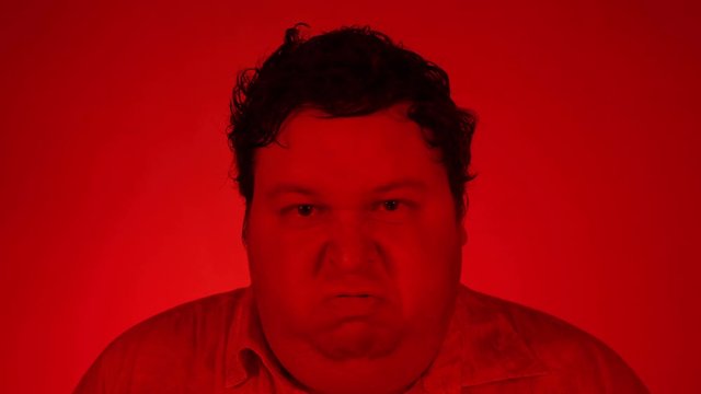 Angry grumpy young man frightened - feeling angry - red lighting