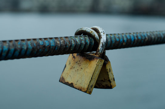 An old rusty padlock hangs on a fence. - Powered by Adobe