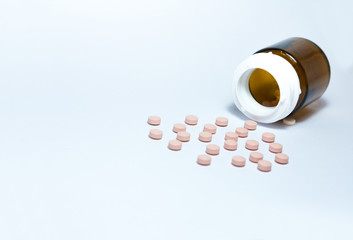 pink medical pills and tablets spilling out of a drug bottle on the white background, top view with copy space for text, health care pharmaceutical medicine concept .