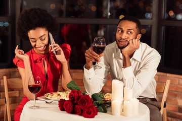 Boyfriend Sitting Bored While Girlfriend Chatting On Phone In Restaurant